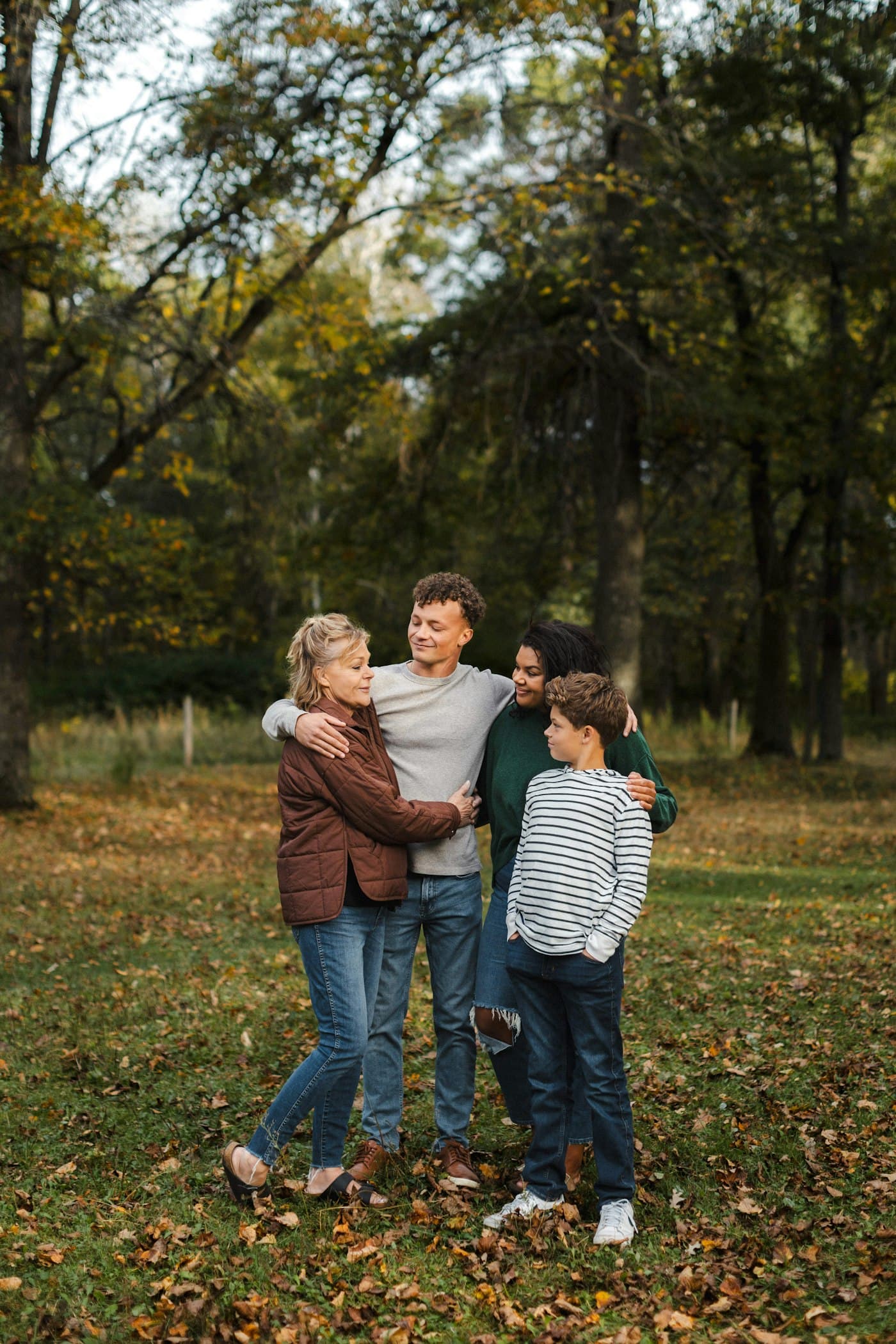 A family of four standing together under autumn trees