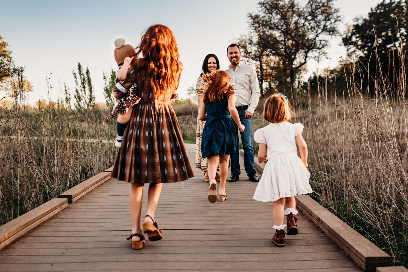 A young family walking on a boardwalk at sunset